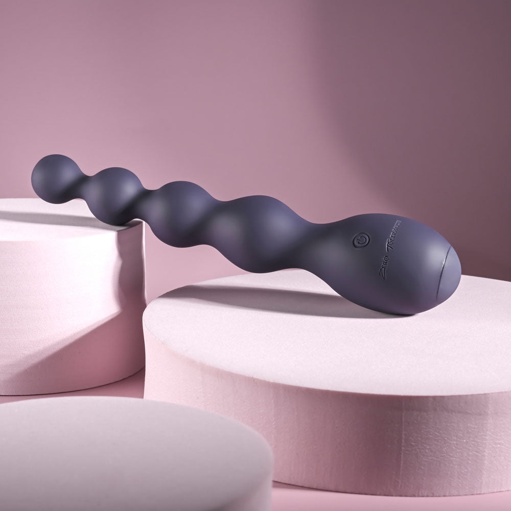 Side view of Zero Tolerance Rumpy Bumpy vibrating anal beads placed against a soft light purple decor, showing sleek curved design | Flirty Bay, anal plug adult store Australia